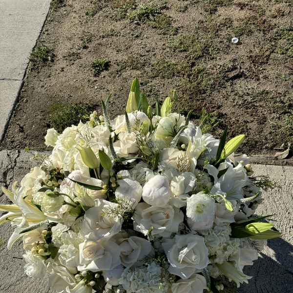 White floral bouquet with lilies and roses on pavement