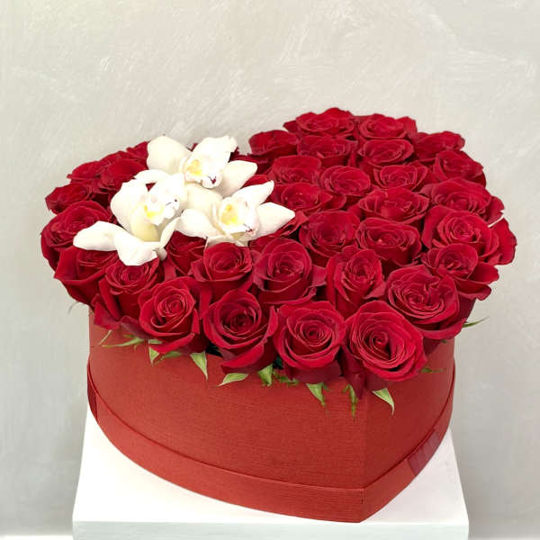 Heart-shaped box filled with red roses and white orchids