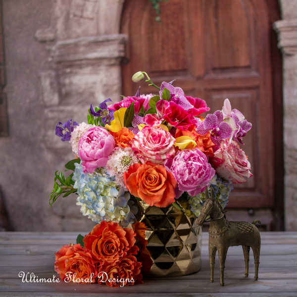 Bright mixed bouquet in a gold vase with a small decorative horse figurine