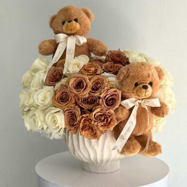 Bouquet of cream and brown roses with two teddy bears in a white vase