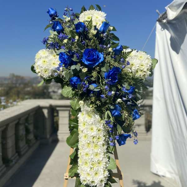 Blue and white floral cross on an easel outdoors