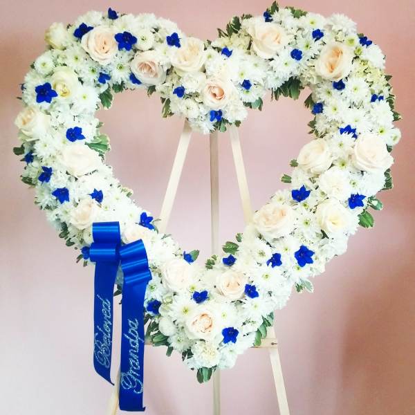 Heart-shaped floral wreath of white and blue flowers on an easel