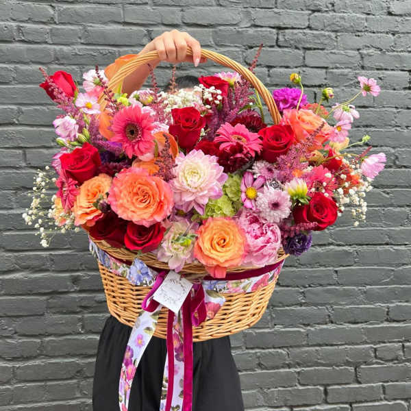 Large wicker basket filled with colorful mixed flowers and ribbon