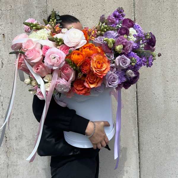 Large bouquet of pink, orange, and purple flowers in a white box