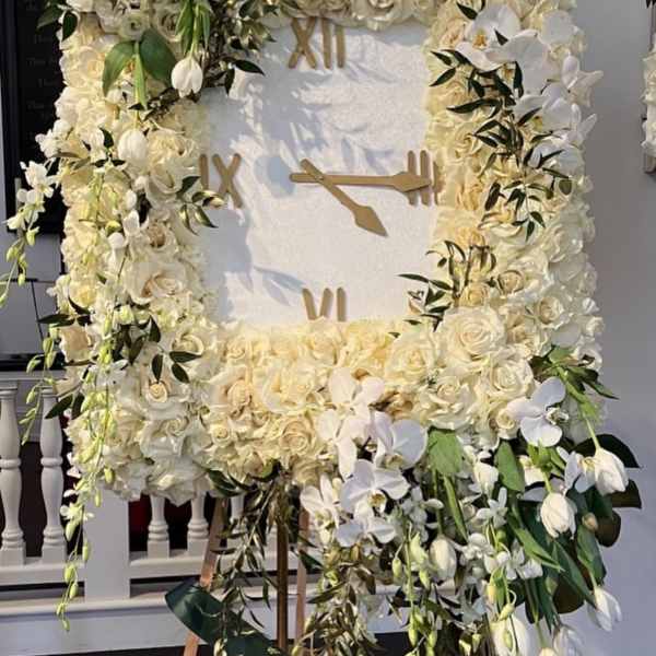 Large white floral clock display with roses and orchids