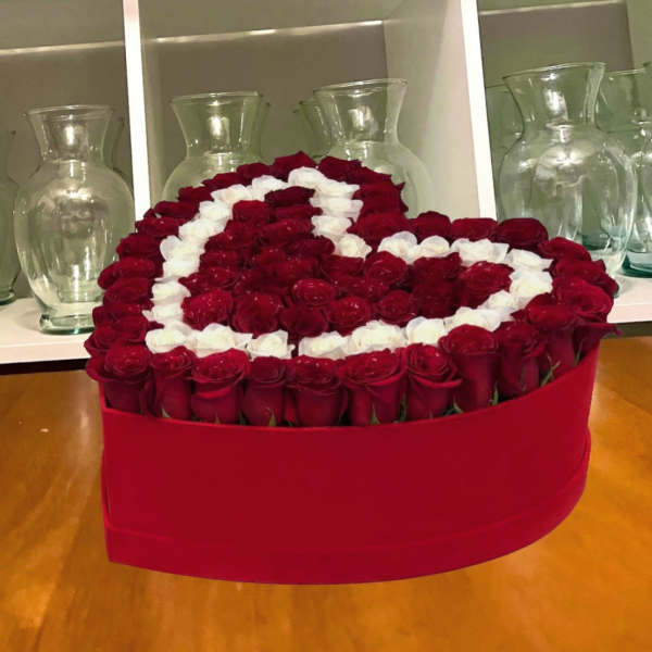Heart-shaped arrangement of red and white roses in a red box