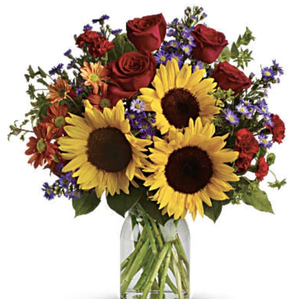 Bouquet of sunflowers, red roses, and mixed purple flowers in a glass vase