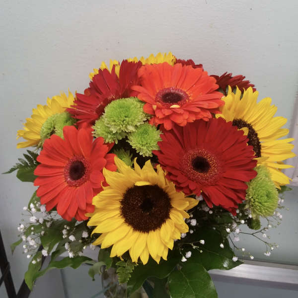Bouquet of red, orange, and yellow gerbera daisies in a glass vase