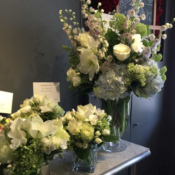 White and pale green floral arrangements in glass vases on a counter