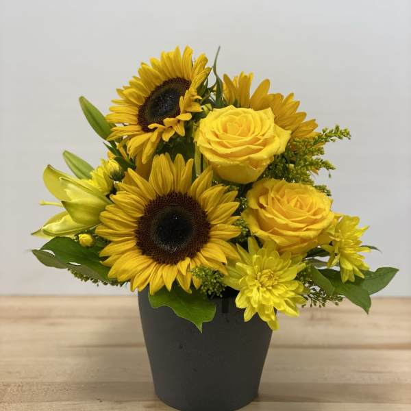 Yellow sunflowers and roses arranged in a black pot
