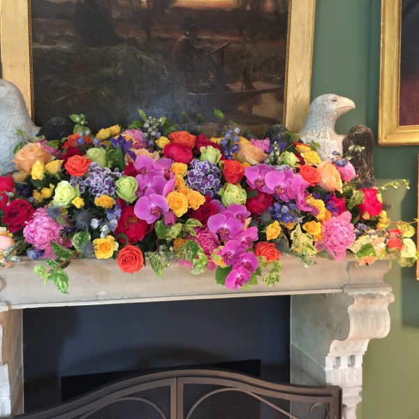 Colorful mixed floral arrangement on a mantel with two bird sculptures