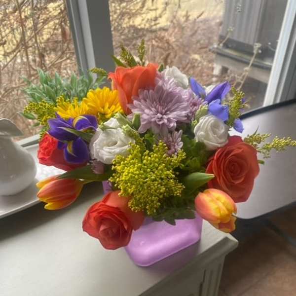Colorful mixed bouquet in a lavender vase on a table