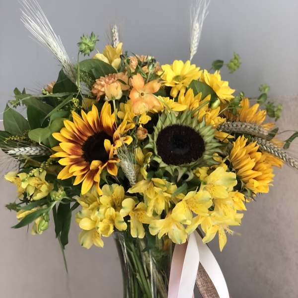 Yellow sunflower bouquet in a glass vase with ribbon