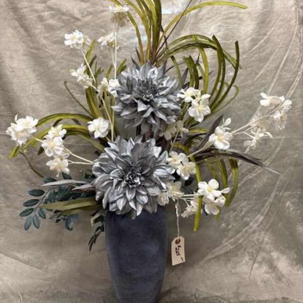 Tall floral arrangement with silver flowers and white blossoms in a dark vase
