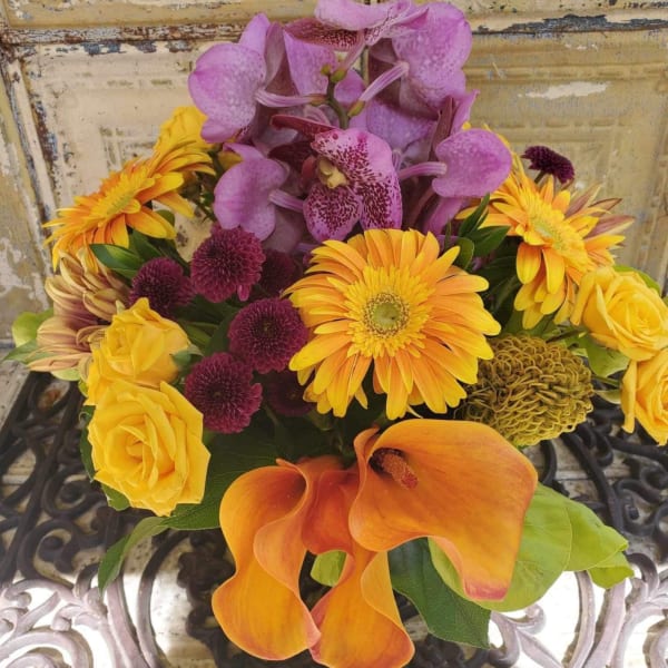Bouquet with purple orchids, yellow roses, orange calla lilies, and mixed daisies