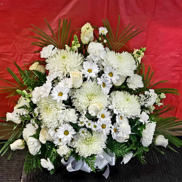 White floral arrangement with daisies and roses in a ribbon-tied base
