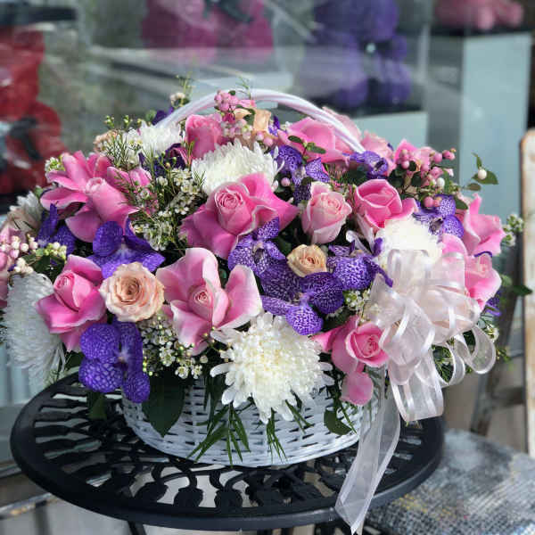 Pink and purple flower basket with roses and orchids in a white basket