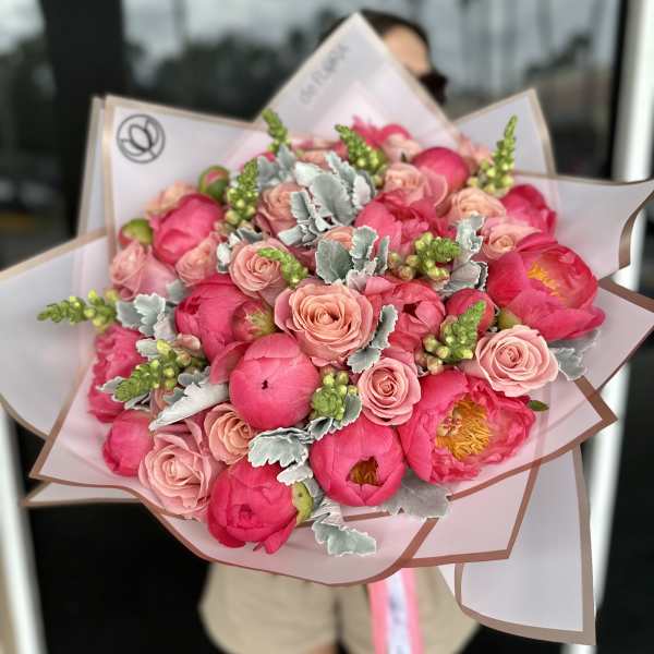 Bouquet of pink peonies and blush roses wrapped in pale paper