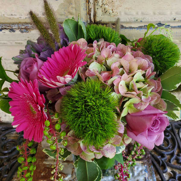 Pink gerberas and roses with hydrangea and green pom-pom blooms in a vase