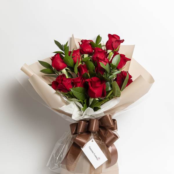 Bouquet of red roses wrapped in beige paper with a brown ribbon