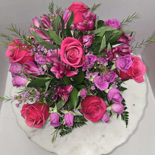 Pink and purple rose bouquet on a white round base