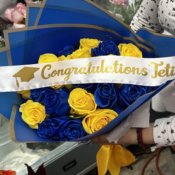 Blue and yellow rose bouquet with a graduation sash