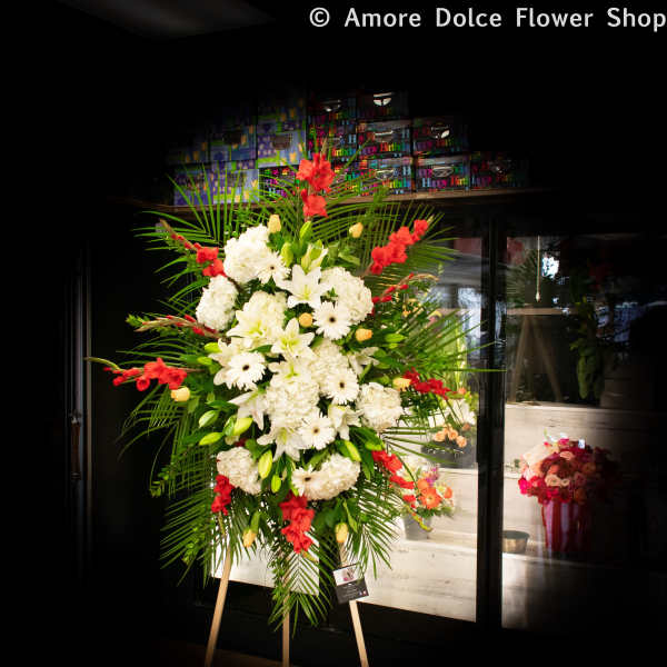 Large standing floral spray with white blooms and red accents on an easel