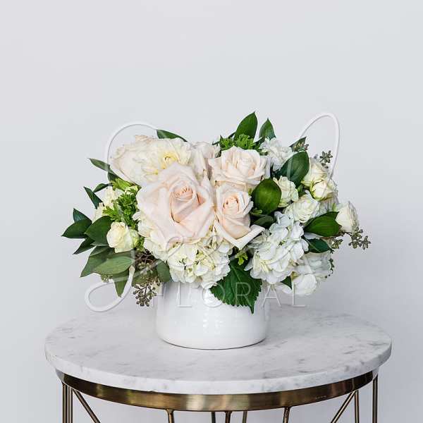 White and blush roses arranged in a white vase