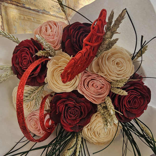 Bouquet of red, blush, and cream roses with wheat and red ribbon accents