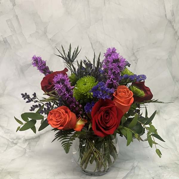Mixed bouquet of red and orange roses in a clear glass vase