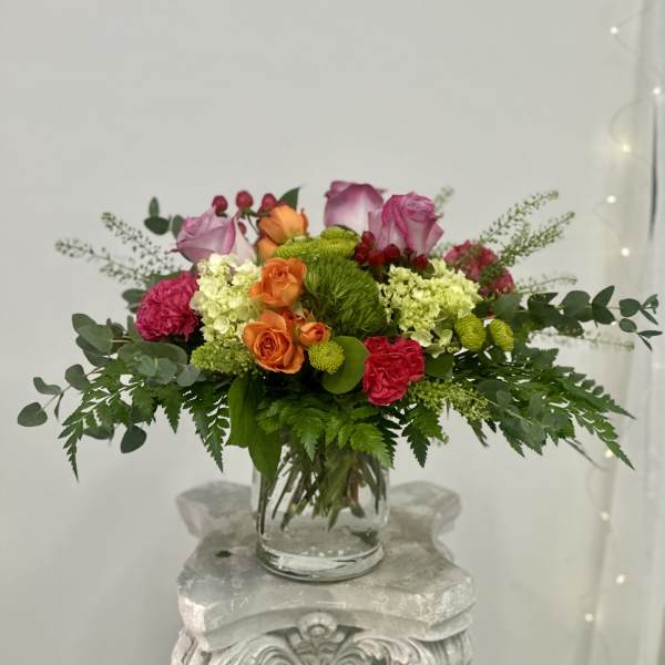 Mixed pink, orange, and green flower arrangement in a clear glass vase