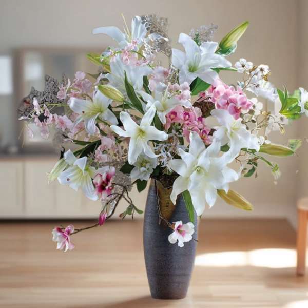 White lilies and pink orchids in a tall dark vase