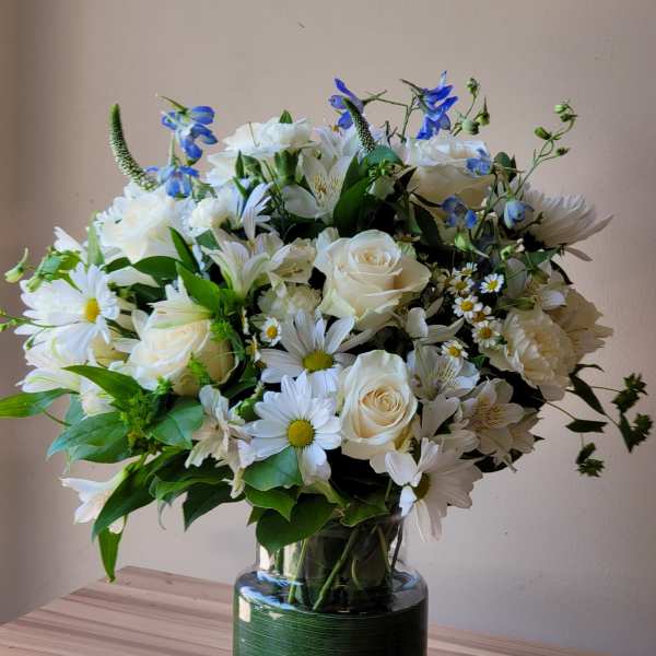 White and blue mixed flower bouquet in a glass vase