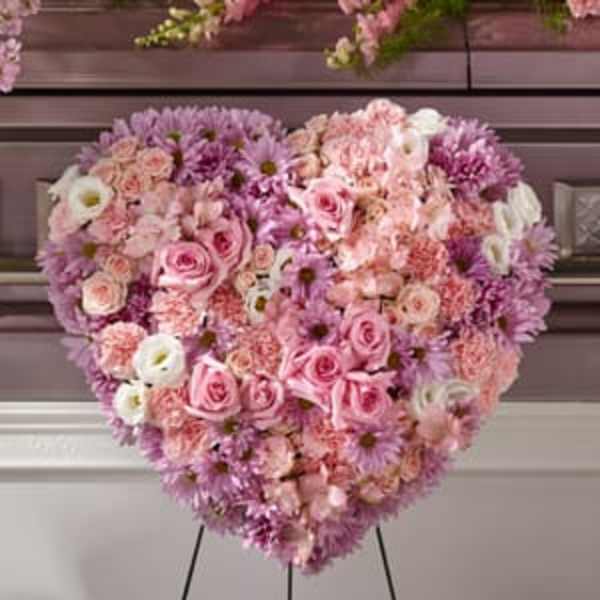 Heart-shaped floral arrangement of pink, lavender, and white blooms on an easel