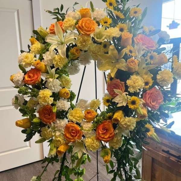 Large floral wreath with orange roses, yellow lilies, and sunflowers