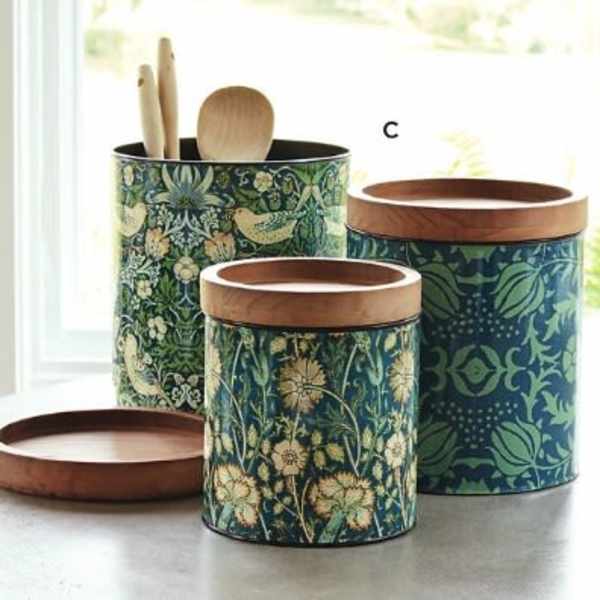 Three patterned canisters with wooden lids and utensils