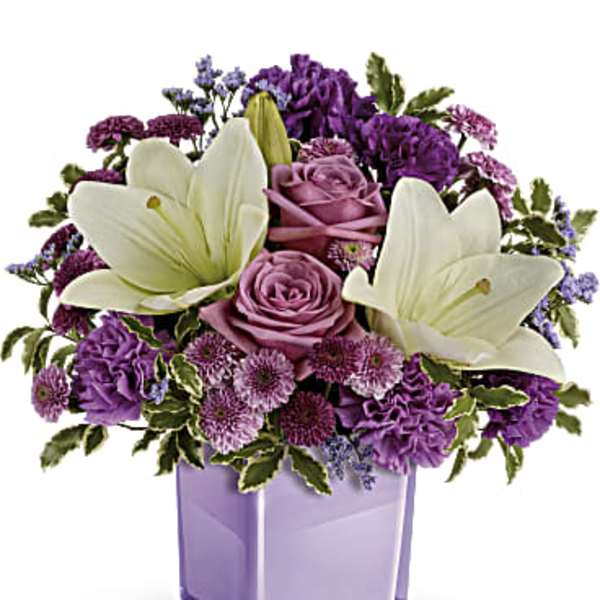 Purple and white floral arrangement in a lavender glass vase