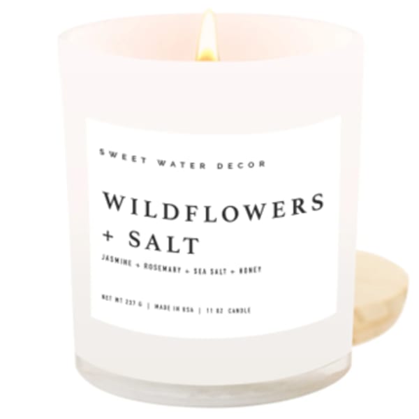 Lit white candle in a glass jar labeled Wildflowers + Salt