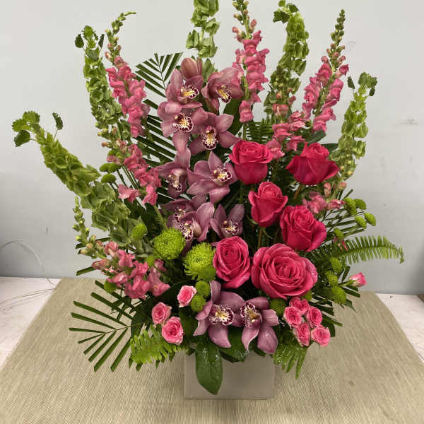 Tall pink and green floral arrangement in a white container