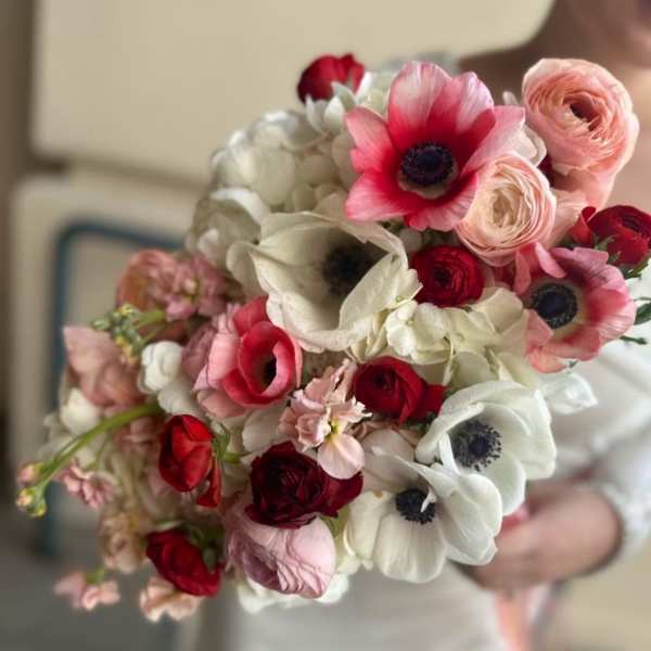 Handheld bouquet of pink, red, and white flowers