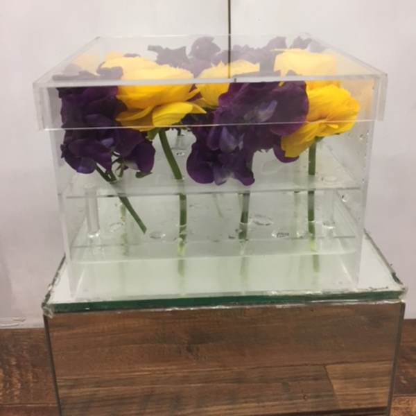 Purple and yellow flowers arranged in a clear acrylic box
