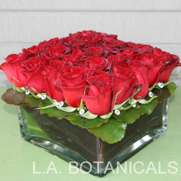 Low square arrangement of red roses in a glass vase