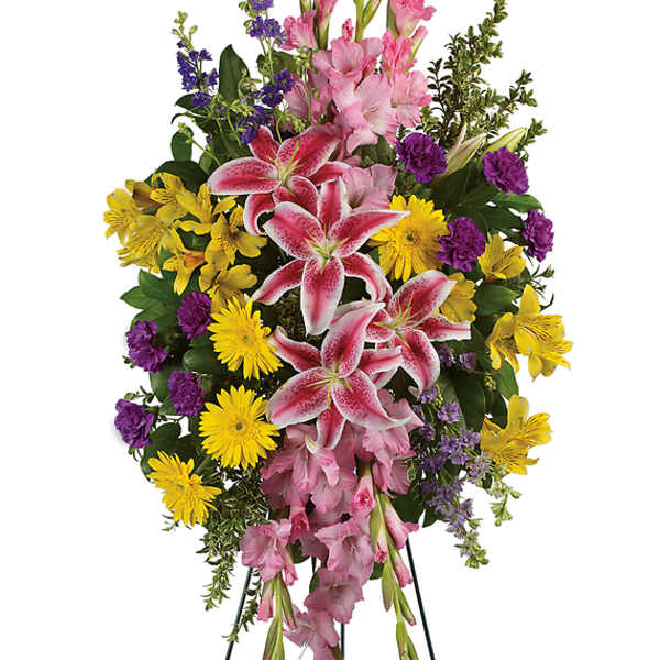 Standing floral spray with pink lilies, yellow daisies, and purple accents