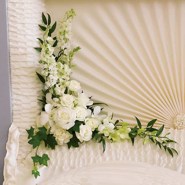 White floral spray with roses and orchids on a cream fan-shaped backdrop