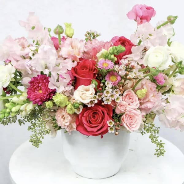 Mixed pink and red flower arrangement in a white vase