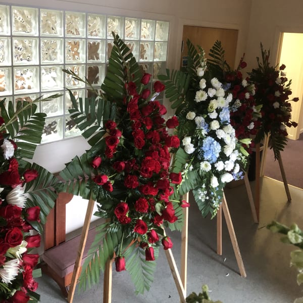 Standing floral sprays with red, white, and blue flowers on easels