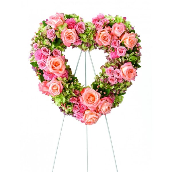 Heart-shaped floral wreath of pink roses and green hydrangeas on a stand