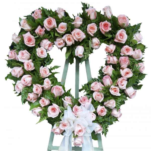 Heart-shaped wreath of pale pink roses with a white ribbon bow