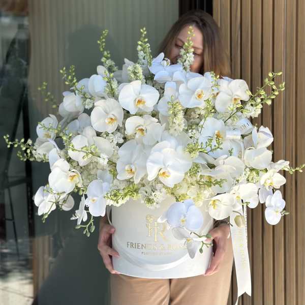 Large white orchid arrangement in a round hatbox