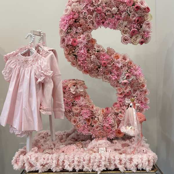 Pink floral number display with a baby dress and gift items